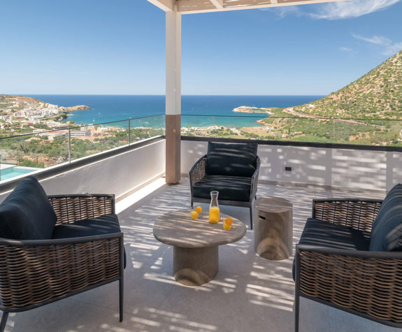 Balcony at Nelisa Villa with wicker armchairs and a round table, overlooking the bay of Bali, Crete.